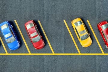 L’immagine mostra un parcheggio con stalli riservati ai disabili, chiaramente contrassegnati da strisce gialle e simboli internazionali per la mobilità ridotta.