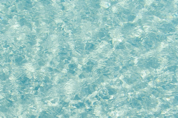 Acqua trasparente e azzurra, calma e profonda, con leggere onde che si muovono lentamente sotto il cielo sereno.