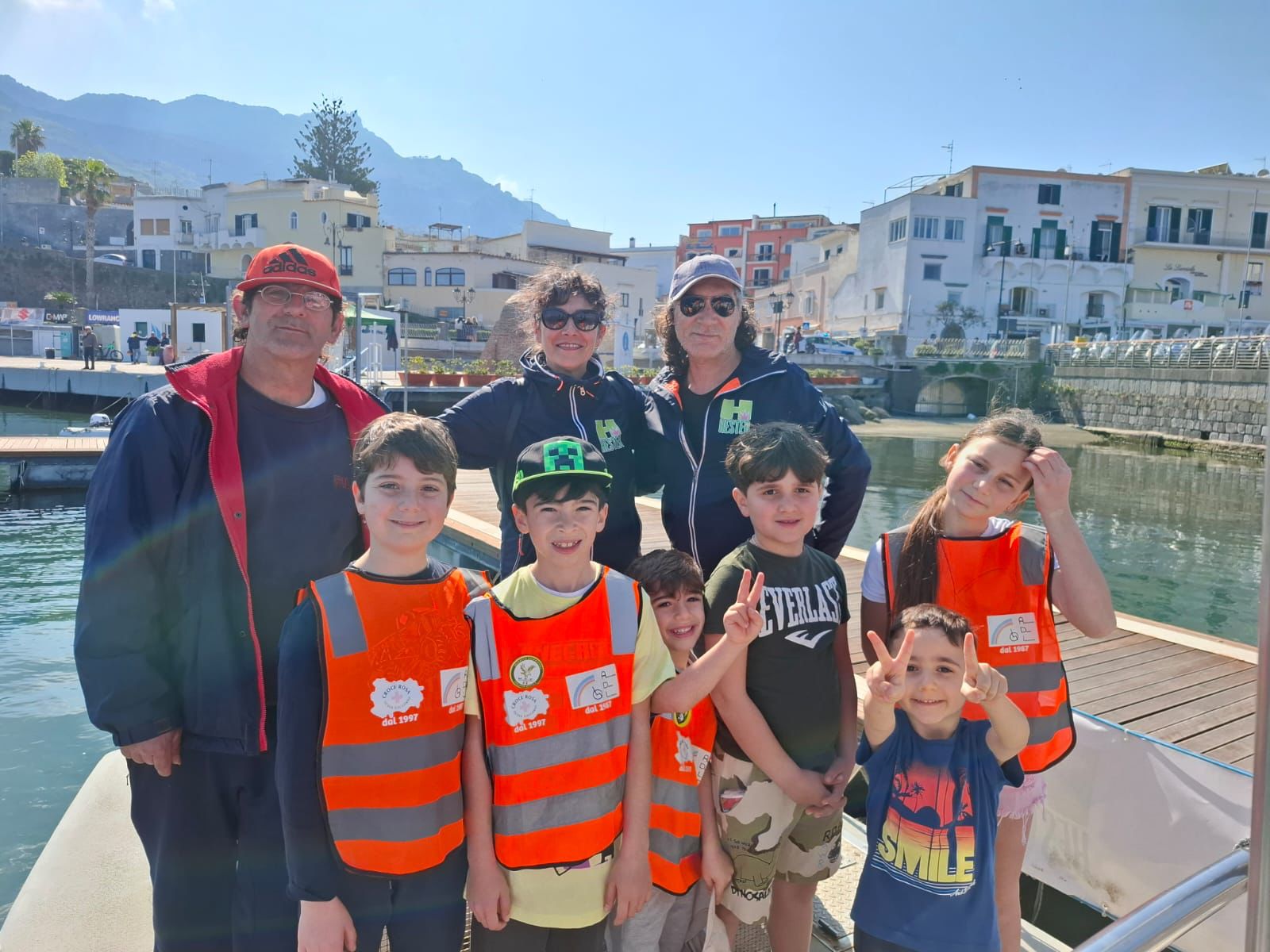 Foto di gruppo vicino al Porto di Forio, con i partecipanti sorridenti e soddisfatti del loro lavoro di pulizia della spiaggia. Il mare e il porto fanno da sfondo, testimoniando l’impegno per un ambiente più pulito e sostenibile.