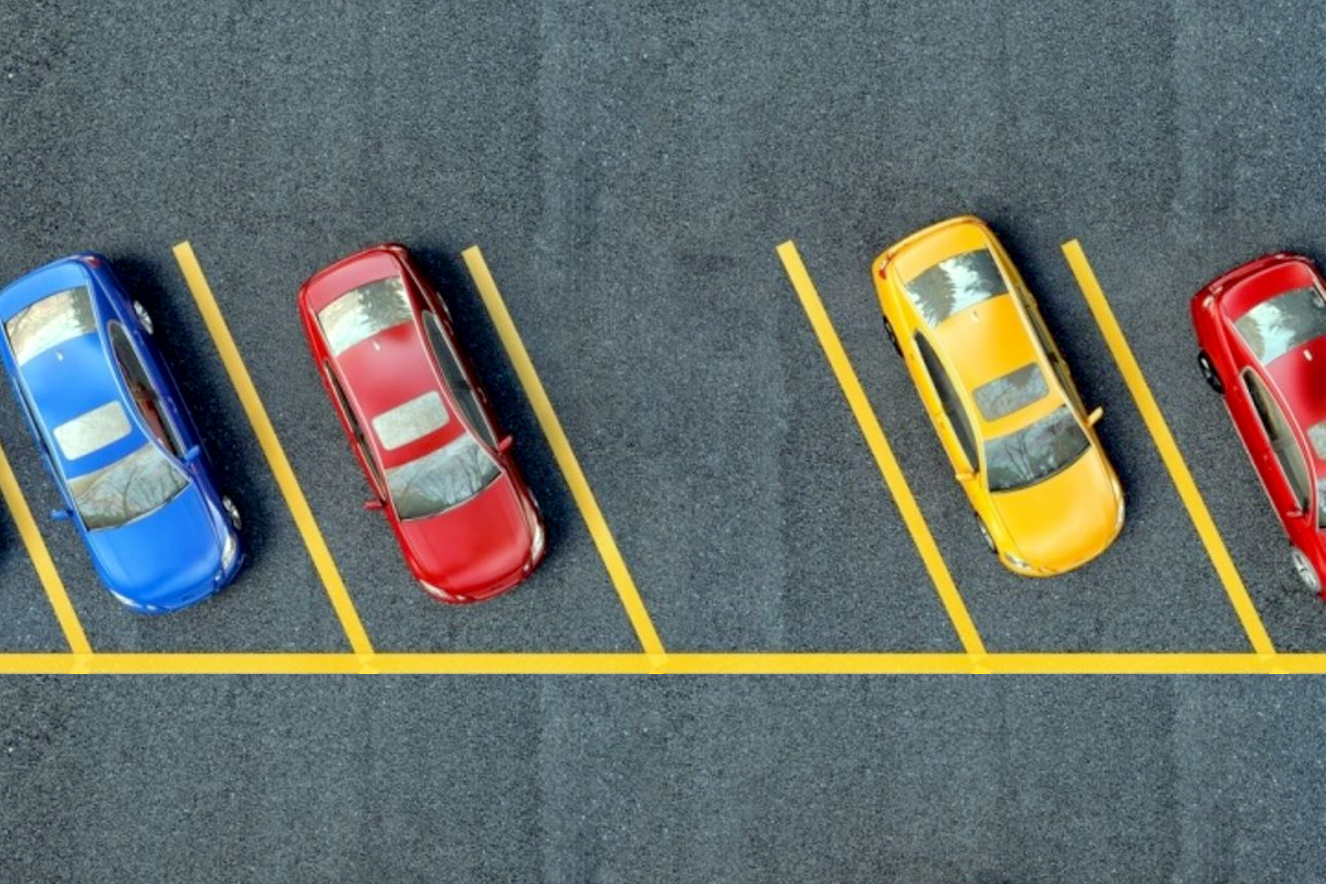 L’immagine mostra un parcheggio con stalli riservati ai disabili, chiaramente contrassegnati da strisce gialle e simboli internazionali per la mobilità ridotta.